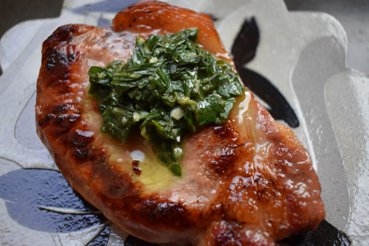 A perfectly seared pork chop with a pistou topping.