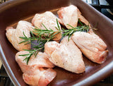 Organic Pastured chicken wings arranged in a shallow ceramic dish.